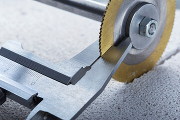 Vernier calipers measure the thickness of a circular saw blade