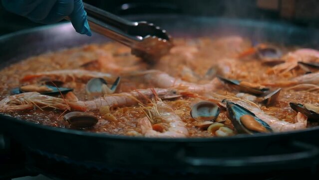 Close up slow motion view seafood paella cooked on frying pan. Traditional Spanish dish. Restaurant main course dish concept