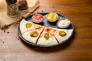 Quesadilla with chicken and sauces on black plate