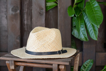 Stylish hat on wooden stool near fence. Beach accessory