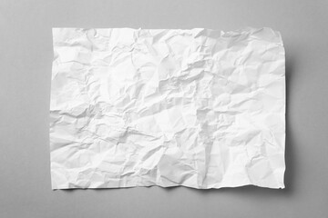 Obraz premium Sheet of white crumpled paper on grey background, top view