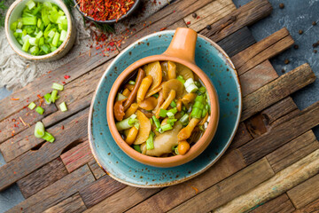 pickled mushrooms in a pot on wooden board