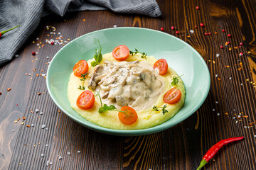 Stroganoff with beef, mushrooms and mashed potatoes on plate on wooden table