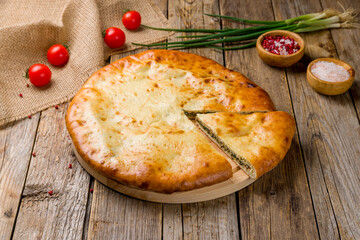 Ossetian pie with spinach on old wooden table