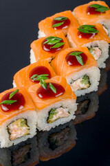 roll with baked salmon and fresh salmon on black with reflection