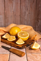 Pieces of lemon on a wooden kitchen board. Fresh lemons cut into slices on a kitchen ceramic table. Top view.