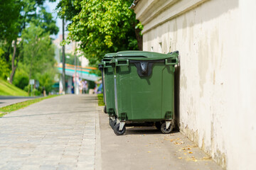 Fototapeta na wymiar Plastic green garbage containers stand in a row near the sidewalk