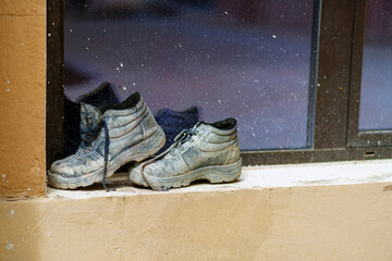 Very dirty black sneakers dry on the windowsill