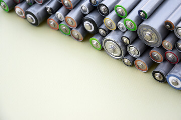 Used AA batteries and proper disposal of environmentally and soil-toxic batteries on a green...
