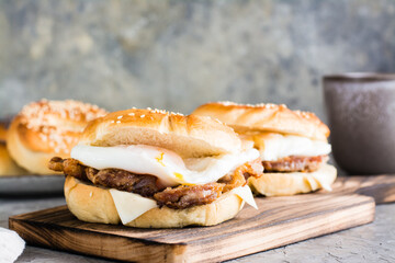 Bagels with fried meat, poached egg and cheese on a board on the table. Homemade fast food