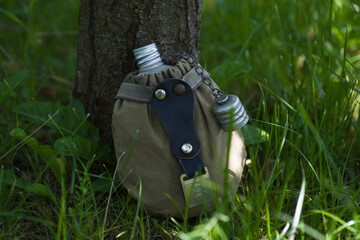 an old army flask is lying in the grass under a tree