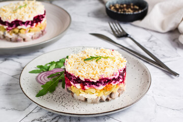 Herring under a fur coat traditional New Year's salad of vegetables and fish on a plate on the table