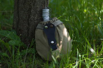 an old army flask is lying in the grass under a tree
