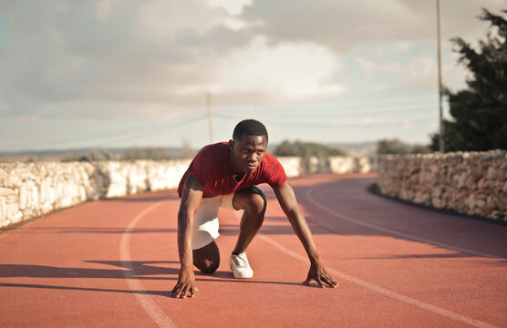 young man ready for athletic sprint on a running track