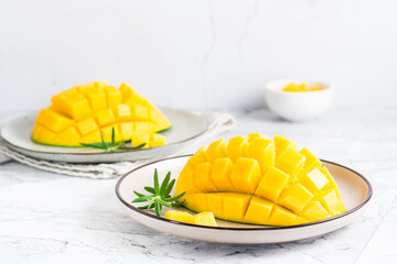 Ripe mango cubes on plates on the table. Tropical fruit