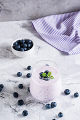 Obraz na płótnie Canvas A glass of blueberry smoothie on the table. Antioxidant organic healthy food. Vertical view
