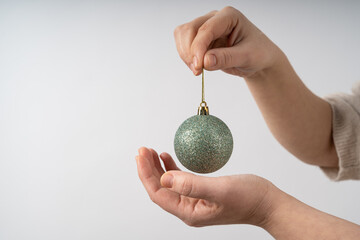 Young woman holds green glittering christmas ball with hands