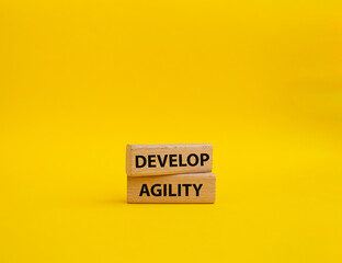 Develop agility symbol. Concept word Develop agility on wooden blocks. Beautiful yellow background. Business and Develop agility concept. Copy space