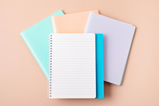 Desktop with notebooks mockup over pastel background. School and office stationary. Back to school, home office, begining of studies concept. Top view, flat lay