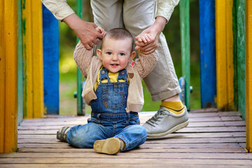 Mother teaches toddler baby boy to walk on the playground