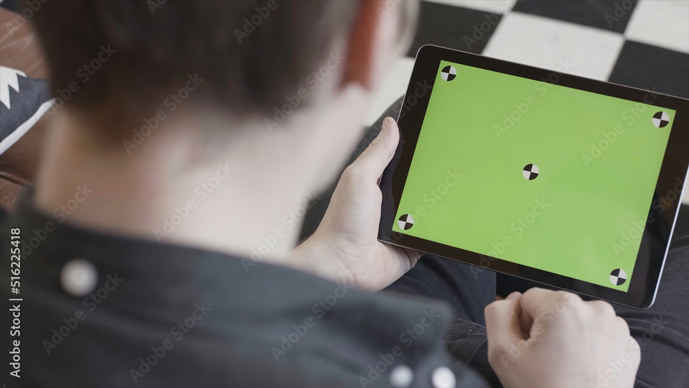 Poster technology and internet concept, over the shoulder view of a man tapping on the green screen of a ta