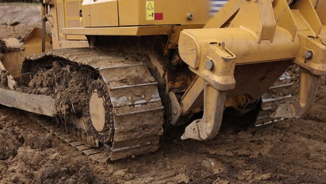 Construction machinery equipment, earth building bulldozer, earthmoving machine technology, industrial erection concept. Bulldozer working on mud at a construction site. Close up