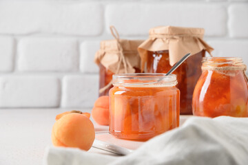 Homemade Apricot jam in glass jar on kitchen white background. Summer harvest and canned food for...