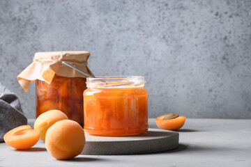 Homemade Apricot jam in glass jar on kitchen white background. Summer harvest and canned food for winter. Tasty dessert. Copy space.
