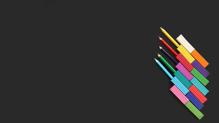 multicolored plasticine and pencils on black background