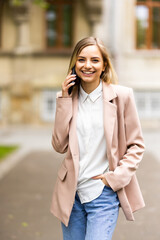 Portrait of young woman talking on the phone while standing outdoors at the street. Business concept.