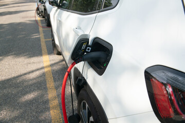 electric car being recharged, connected with the red cable to the electrical control unit, where it...