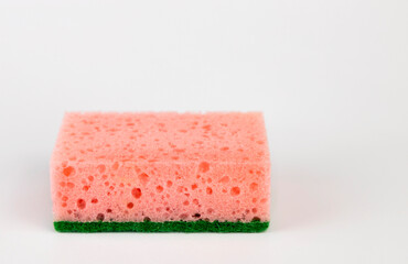 Foam sponge for washing dishes in pink color, close-up on a white background.