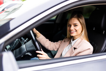 Fototapeta na wymiar Happy young success happy brunette woman is driving a car. Portrait of happy female driver steering car with safety belt