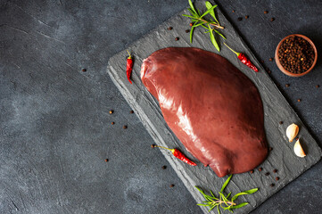 Raw Beef liver meat on stone board with thyme and black peppers, cattle giblets