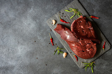 Raw Beef liver meat on stone board with thyme and black peppers, cattle giblets - obrazy, fototapety, plakaty