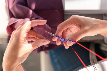aerial view of hands cutting threads from a piece of fabric with scissors