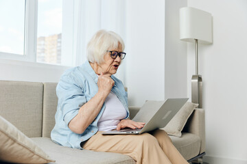 an elderly lady looks at a laptop monitor showing her fist while talking via video link while at home