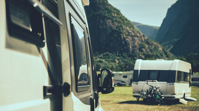 Camper Van and A Travel Trailer in a Background Staying Inside a RV Park