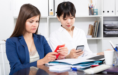 Two businesswomen working with smartphone in the office. High quality photo