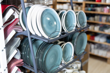 Variety of plates displayed on shelving in household goods store. Kitchen utensils and dishware for...