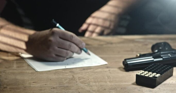 A man writes a farewell letter and reaches for a gun