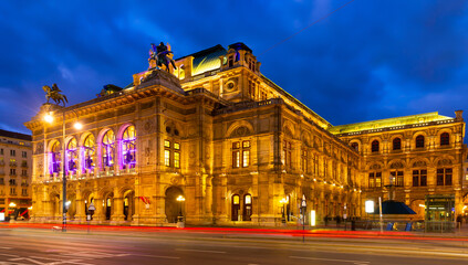 Picturesque view of central avenue of Vienna and illuminated impressive building of famous State Opera at cloudy winter twilight, Austria.