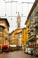 View of central street of historical Italian city of Bergamo decorated with Christmas garlands on winter day 