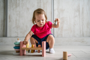 Obraz na płótnie Canvas one child small caucasian girl little toddler playing with educational toys at home childhood and growing up early development concept copy space front view
