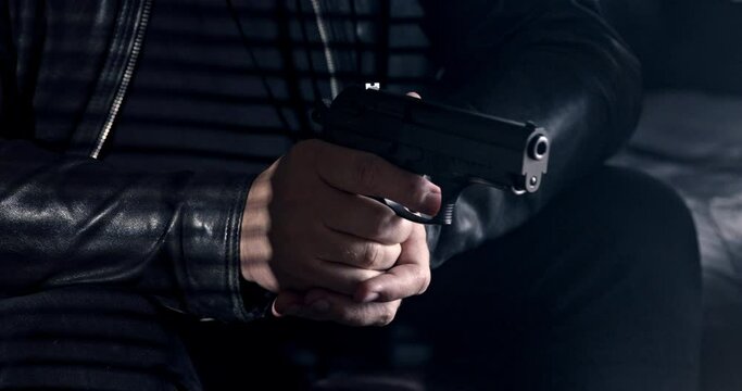 killer or gangster's hand with a gun in the dark