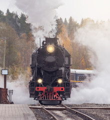 Naklejka na ściany i meble Retro steam train arrives to the station wooden platform. Ruskeala Mountain Park. Republic of Karelia.