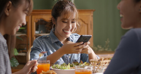 Asia young smart casual girl group friend sit at indoor coffee shop table enjoy laugh fun eat food drink lunch meal party at cafe. Relax look read e-mail text, money trade or post IG reel story app.