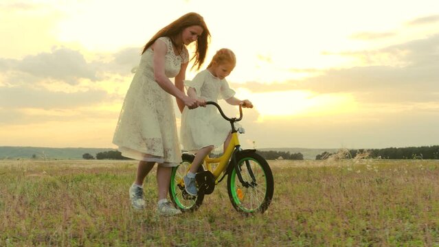 happy family. child girl learning ride bike. mom daughter kid spend time bike park. concept children dream. mother child play outdoors. little girl pedals steers bicycle park. young mother with kid.