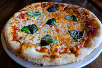 Italian margherita pizza on a wooden table (side shot)