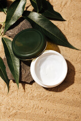 round container for cosmetic products on a background of sand 